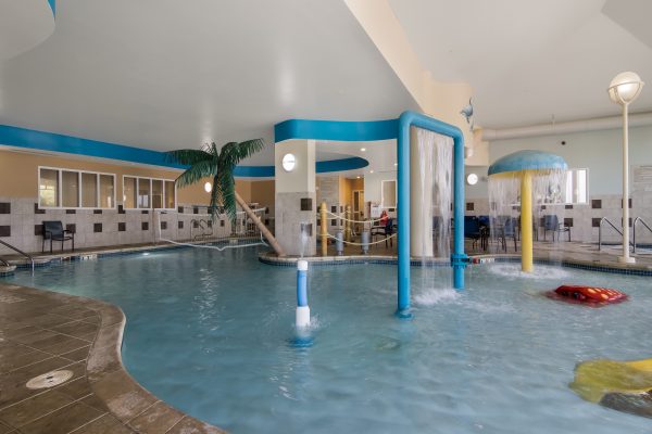 An indoor pool with a slide and water play area.