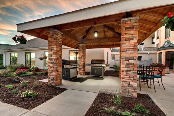 A covered patio with a grill and a fire pit.