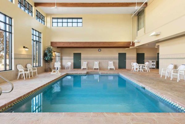 An indoor swimming pool with chairs and windows.