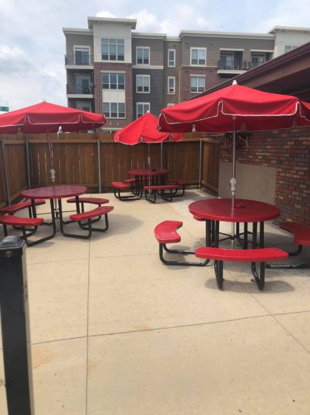 A patio with red umbrellas and picnic tables.