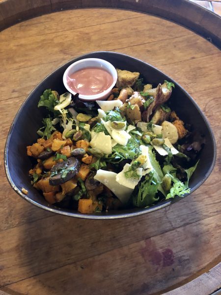 a bowl of salad on a wooden table.