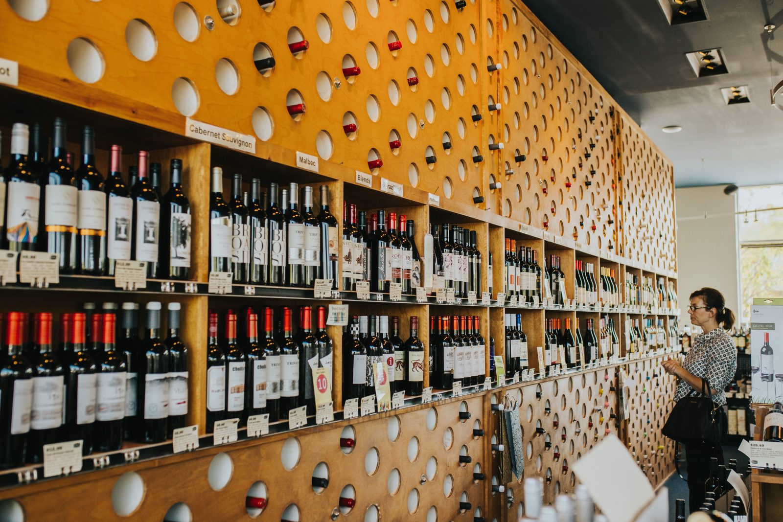 a woman standing in front of a wall of wine bottles.