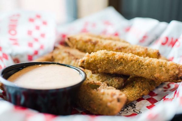 fried pickles with dipping sauce on a plate.