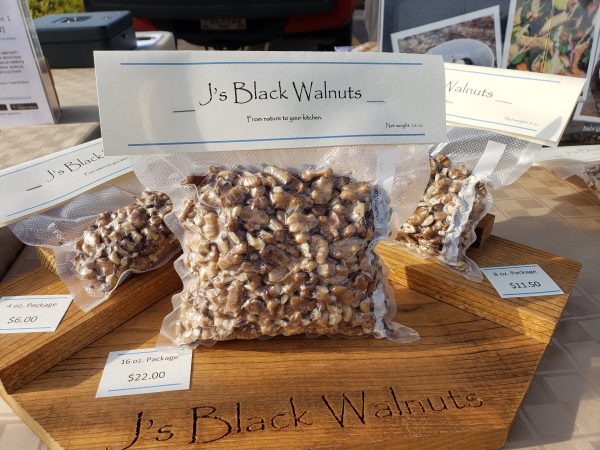 a bag of black walnuts sitting on top of a wooden cutting board.