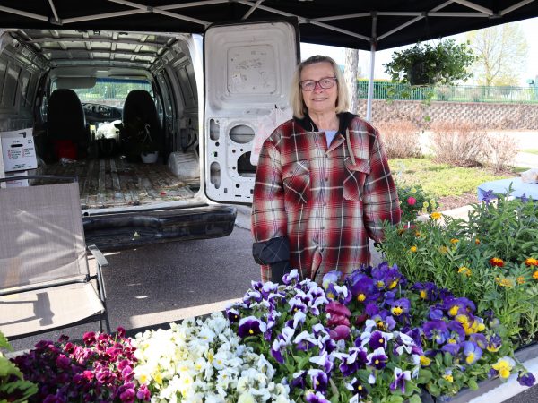 a woman standing in front of a van filled with flowers.