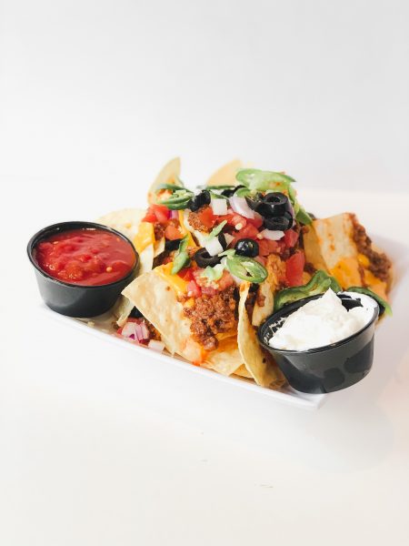 a plate of nachos with salsa and dipping sauce.