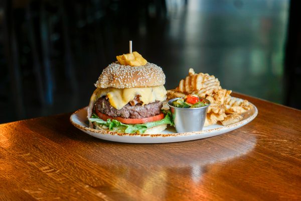 A burger and fries on a plate on a wooden table.
