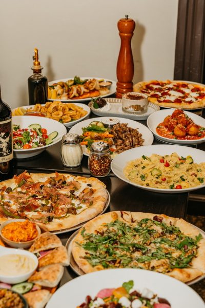 A table filled with various Italian dishes, including pizzas, pasta, salads, meatballs, antipasto, and condiments—plus Villa Dolce gelato to complete the meal.