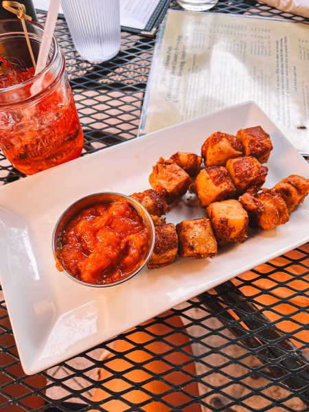 A plate of skewered meat with a sauce on it.