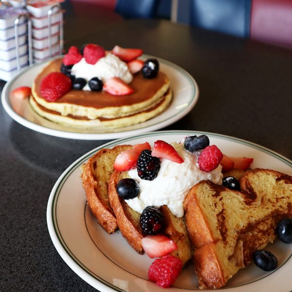 A plate of french toast with berries and whipped cream.