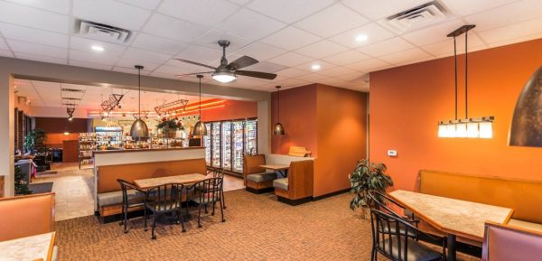 The interior of a restaurant with orange walls and a ceiling fan.