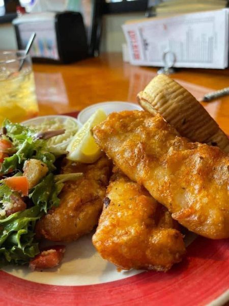 A plate of fish and chips with a salad on it.