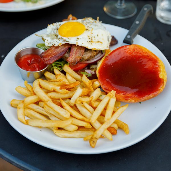 A plate of french fries and a burger with ketchup on it.