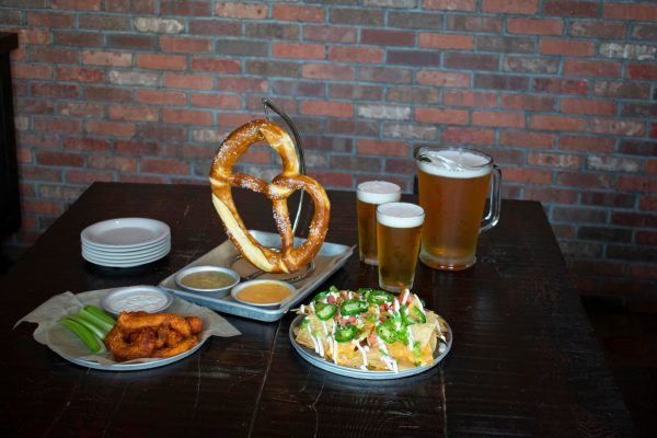 A table with pretzels, wings, beer and pretzels.