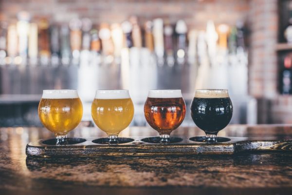 Four different beers are lined up on a bar.