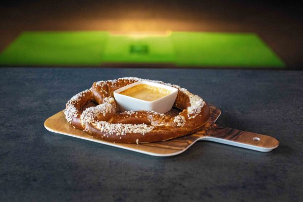 A pretzel on a plate with a bowl of dip.
