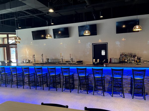 A bar with blue lighting and stools.
