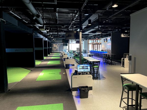 An indoor golf course with green grass and a bar.