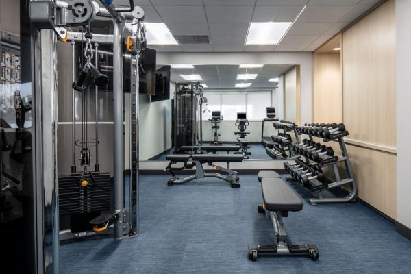 A gym room with equipment and mirrors.