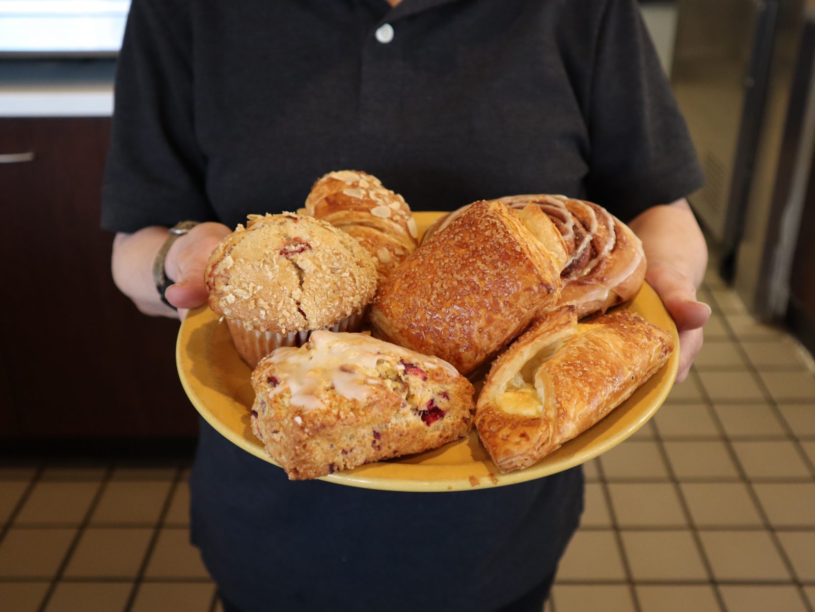 A woman holding a plate full of pastries.