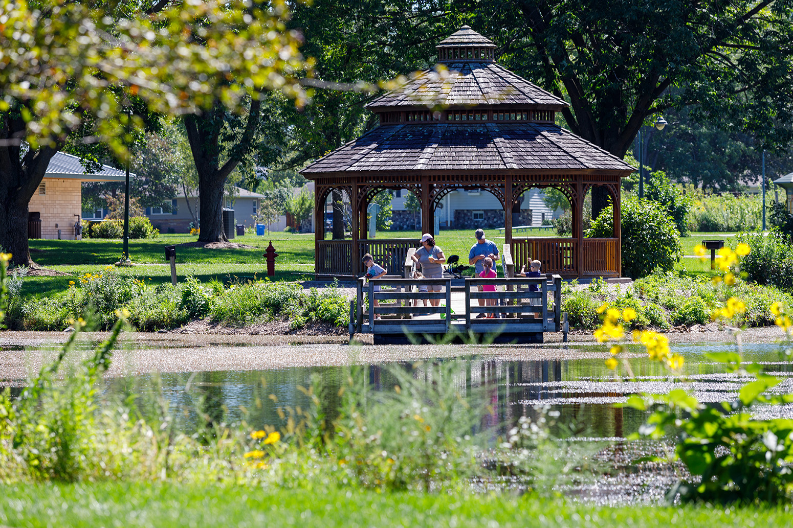 a gazebo in a park with people sitting on it.