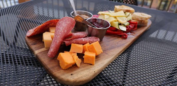 a wooden cutting board topped with meat and cheese