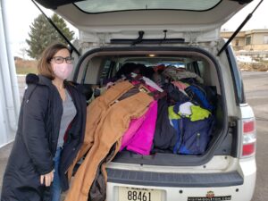 a woman standing in the back of a van filled with clothes