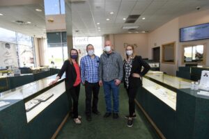 a group of people wearing face masks standing in a jewelry store