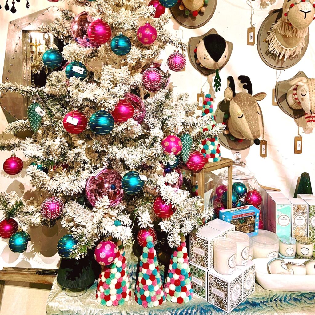 Holiday shopping: Christmas tree with presents and brightly colored decorative smaller trees; on the wall are mounted stuffed animal heads (toys)