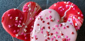two heart shaped cookies sitting on top of a glass plate