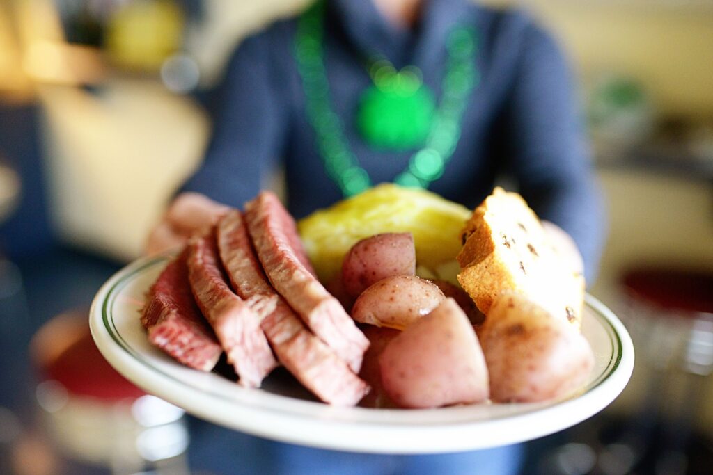Person holding plate of corned beef and cabbage from Hubbard Avenue Diner