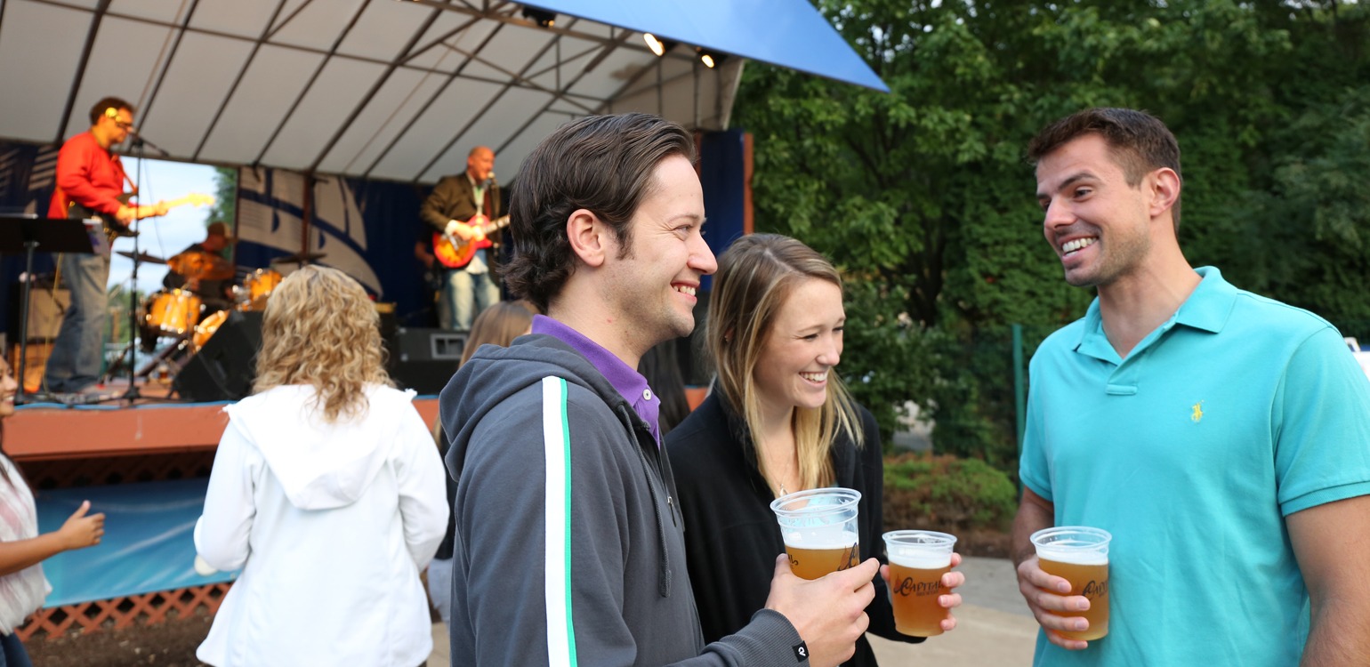 a group of people standing next to each other holding beers