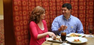 a man and a woman sitting at a table with plates of food