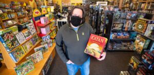 a man wearing a black mask holding a book in a store