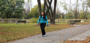 a woman in a blue jacket is jogging in a park