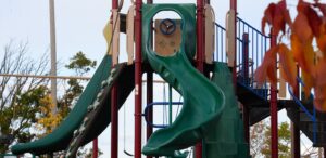 a playground with a green slide and a blue and yellow slide