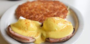 a white plate topped with a sandwich covered in hollandaise