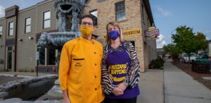 a man and a woman in yellow and purple are standing in front of a fountain