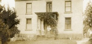 an old photo of two people standing in front of a house