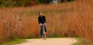 a woman riding a bike down a dirt road