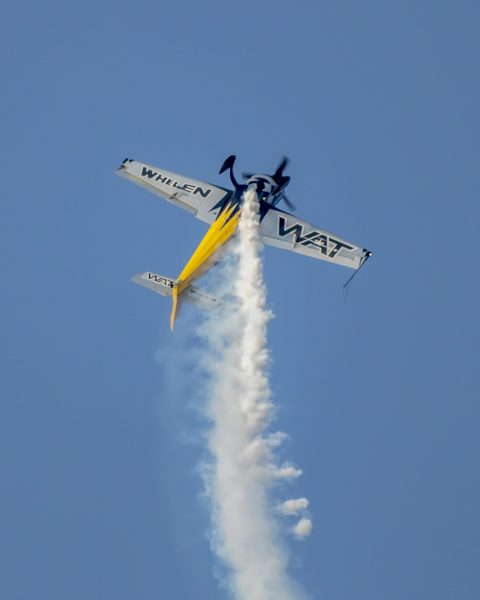 a small plane flying through a blue sky.