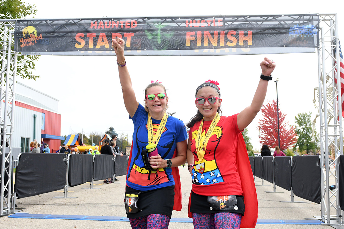 Two women standing on the finish line of a race.