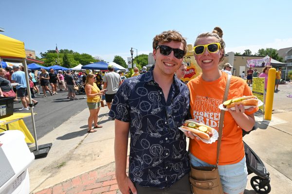 A man and woman pose with their National Mustard Day hotdogs during the festival in Middleton, 2023.
