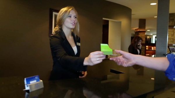 a woman handing another woman a piece of paper