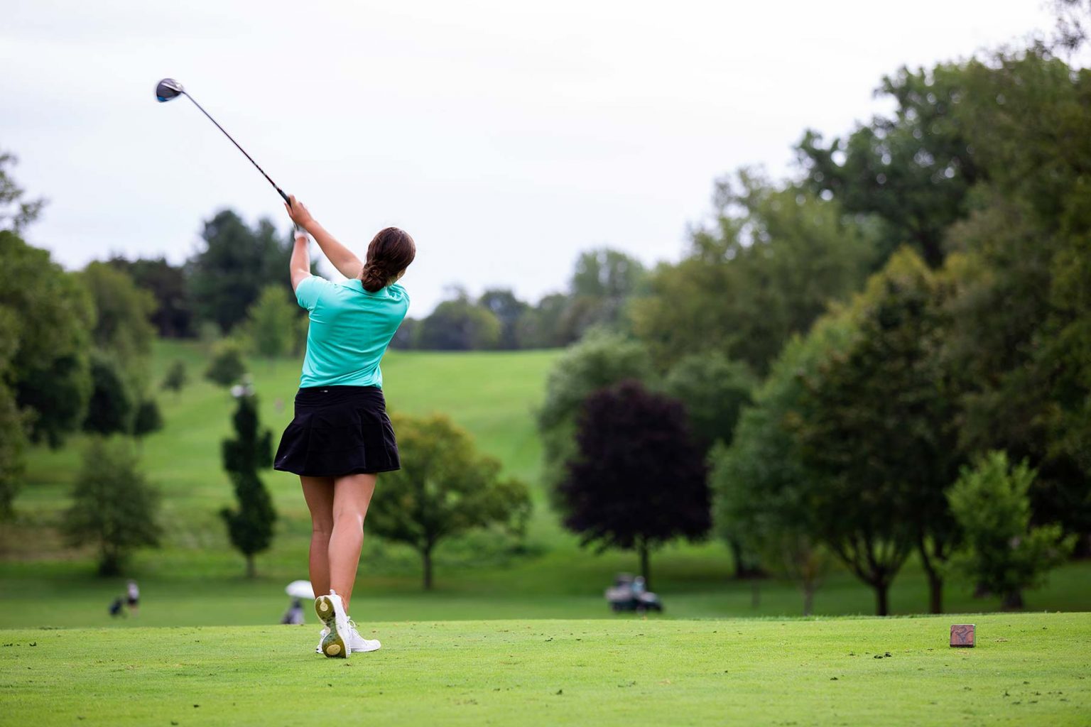 a woman swinging a golf club on a golf course