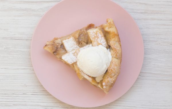 a pink plate topped with a slice of pie and ice cream.