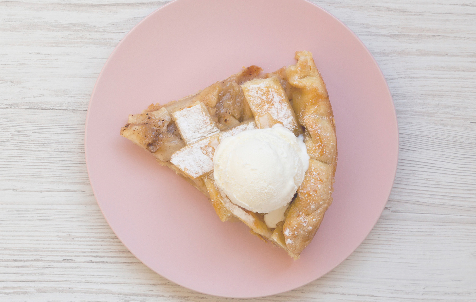 a pink plate topped with a slice of pie and ice cream.