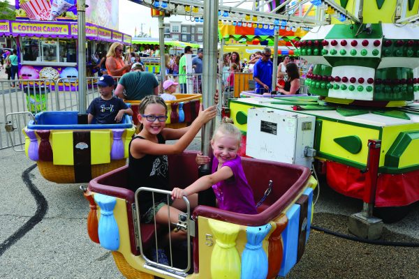 two children riding a carousel at an amusement park.