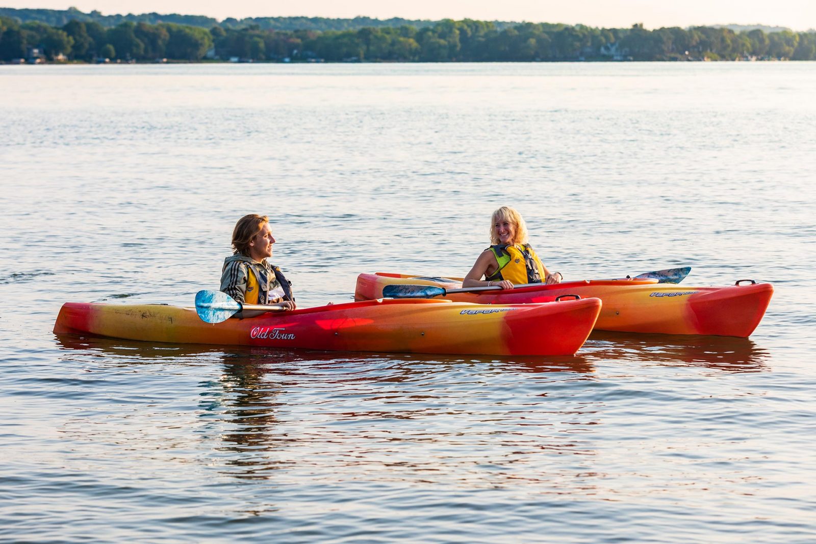 two people in a red and yellow kayak in the water.