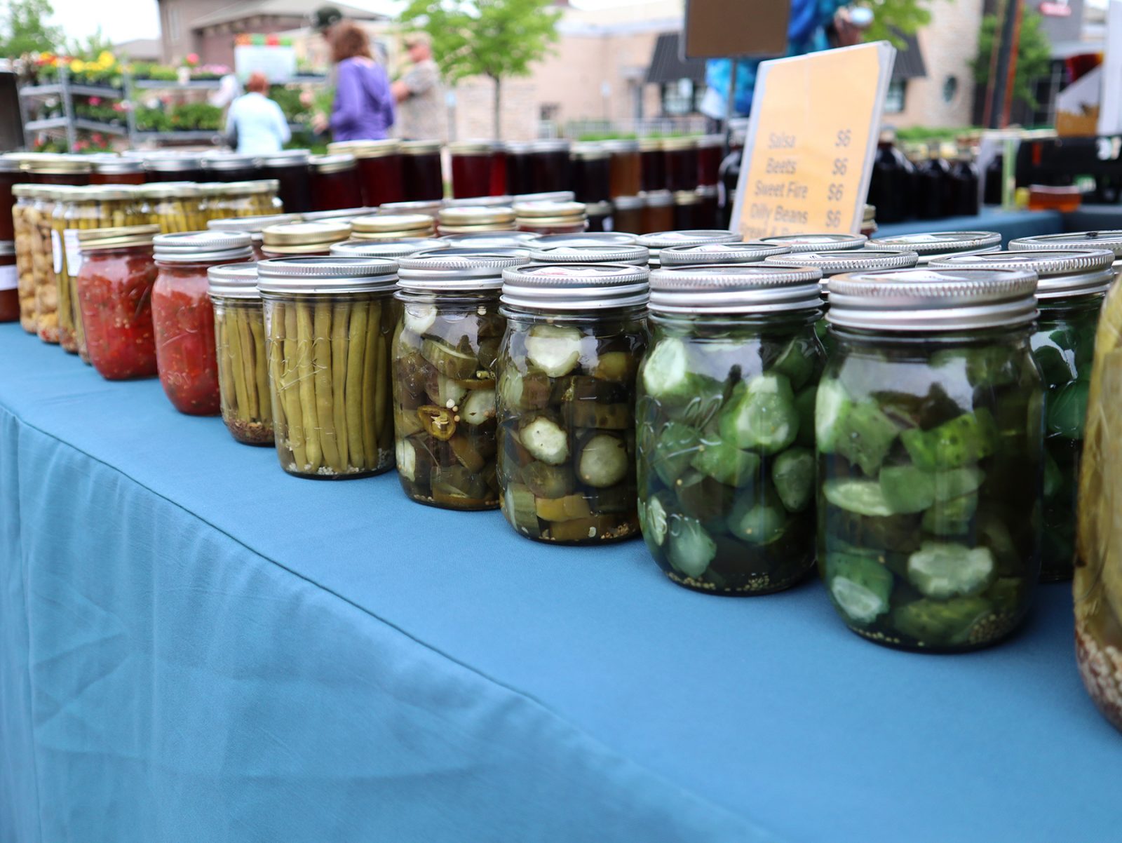 a row of jars filled with pickles on top of a blue table.